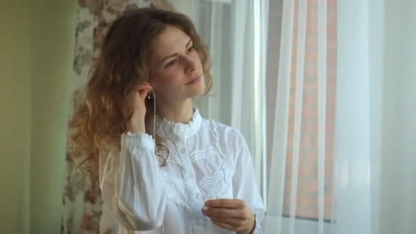 Pelo rizado chica, escuchar música en los auriculares en la ventana, bailar, cantar. retrato — Vídeo de stock