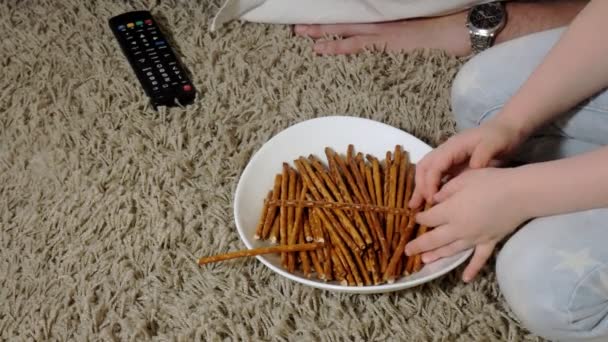 Homem e filha assistindo televisão, sentado no chão comendo lanches — Vídeo de Stock