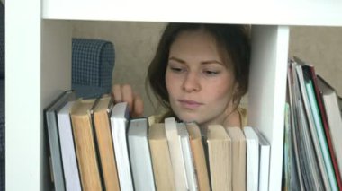 genç kadın bir kitap için arama. Öğrenci Seçme kitaplık Kütüphane. kadın alarak kitap raf Kitaplığı'nda.