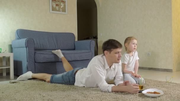男と娘はテレビを見て、菓子を食べて床に座って — ストック動画