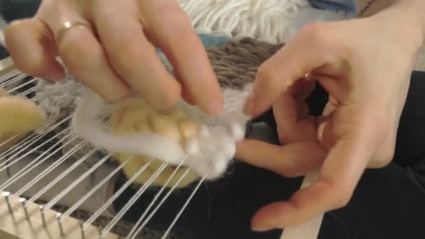 En kvinna väver på en vävstol en vackra broderier gjort av garn, i en hemmastudio, — Stockvideo