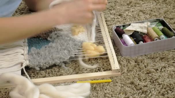 Uma mulher tece em um tear um belo bordado feito de fios, em um estúdio em casa , — Vídeo de Stock
