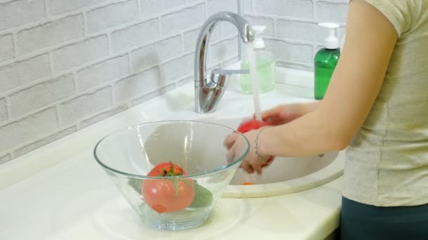 台所の流しの蛇口の下の女性の洗浄の新鮮な野菜はガラスのコップにそれらを置く — ストック動画