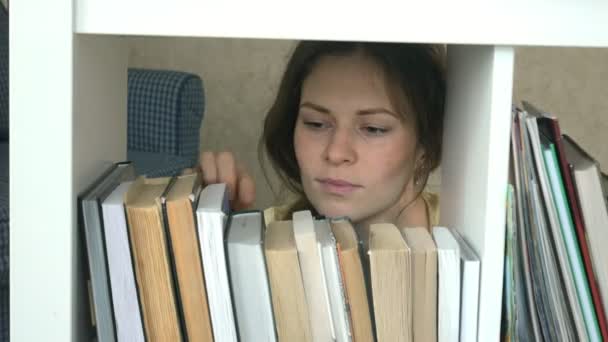 Jonge vrouw zoekt een boek. student selecteren bookshelf-bibliotheek. vrouwelijke nemen boek van de plank in de bibliotheek. — Stockvideo