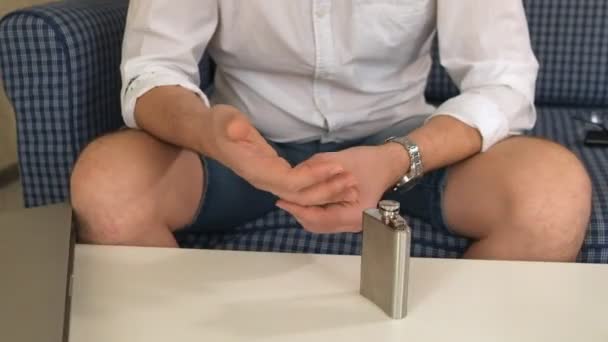 Man in right hand flask with alcohol, in left engagement ring. thinks, divorce. close-up — Stock Video