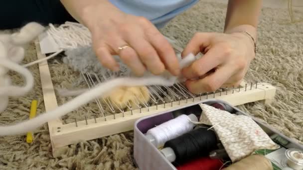 Женщина плетет на ткацком станке красивую вышивку из пряжи, в домашней студии , — стоковое видео
