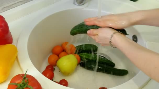 Mujer lava verduras frescas bajo el grifo en el fregadero en la cocina — Vídeos de Stock