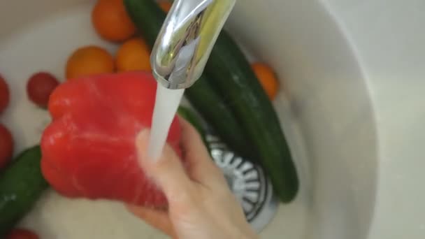 Mujer lava verduras frescas bajo el grifo en el fregadero en la cocina — Vídeo de stock