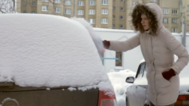 Νεαρή γυναίκα καθαρό αυτοκίνητο μετά από θύελλα χιονιού με ξύστρα — Αρχείο Βίντεο