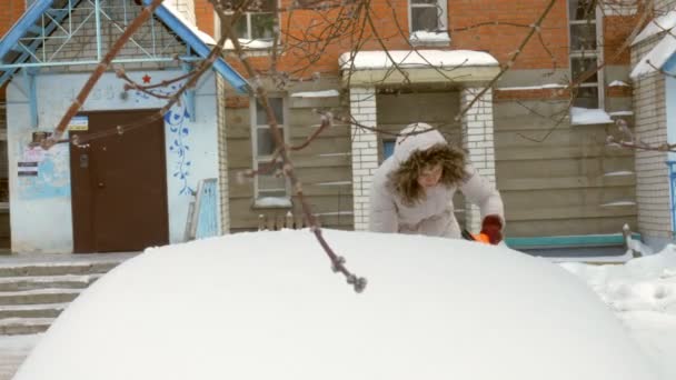 Jeune femme propre voiture après tempête de neige avec grattoir — Video