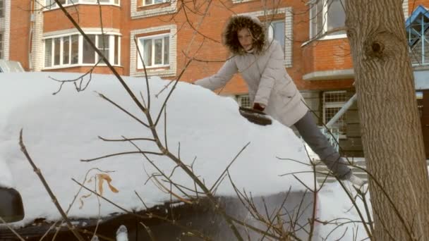 Jonge vrouw schone auto na sneeuwstorm met schraper — Stockvideo