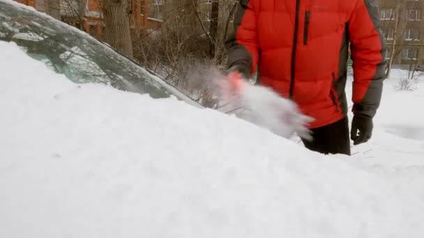 Чоловік чистий автомобіль після снігової бурі зі скребком — стокове відео
