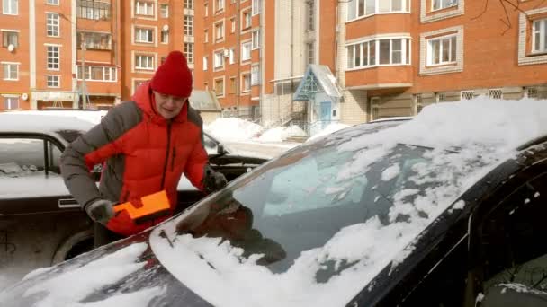 Чоловік чистий автомобіль після снігової бурі зі скребком — стокове відео