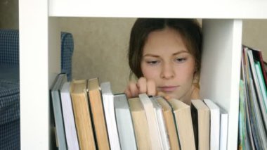 genç kadın bir kitap için arama. Öğrenci Seçme kitaplık Kütüphane. kadın alarak kitap raf Kitaplığı'nda.