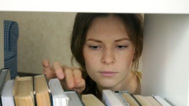genç kadın bir kitap için arama. Öğrenci Seçme kitaplık Kütüphane. kadın alarak kitap raf Kitaplığı'nda.