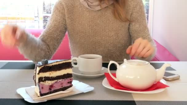 Close-up mão feminina acariciando a xícara de chá no café. Mulher em restaurante com bebida quente e bolo — Vídeo de Stock