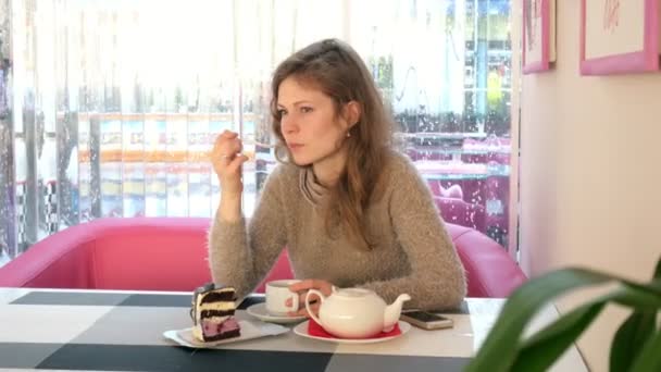 Mano femminile accarezzando la tazza di tè nel caffè. Donna in ristorante con bevande calde e torta — Video Stock