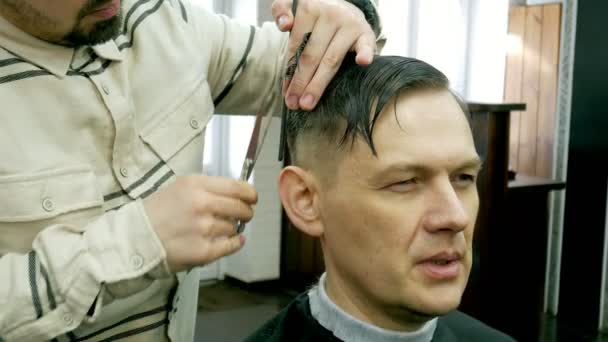 Barbeiro corta o cabelo do cliente com tesoura — Vídeo de Stock