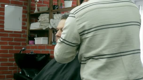 Peluquero corta el cabello del cliente con tijeras — Vídeos de Stock