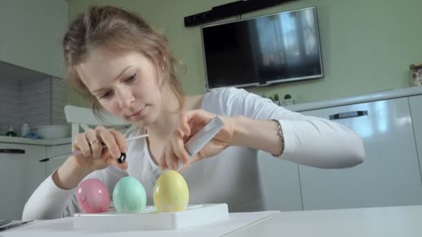 Egy nő húsvéti tojást fest a színes festékek, közeli kép