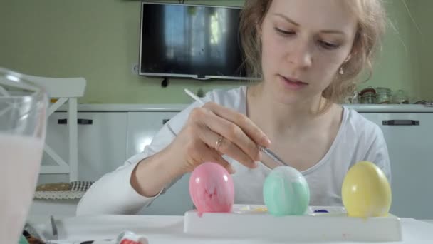 Uma mulher pinta ovos de Páscoa com tintas coloridas, close-up — Vídeo de Stock