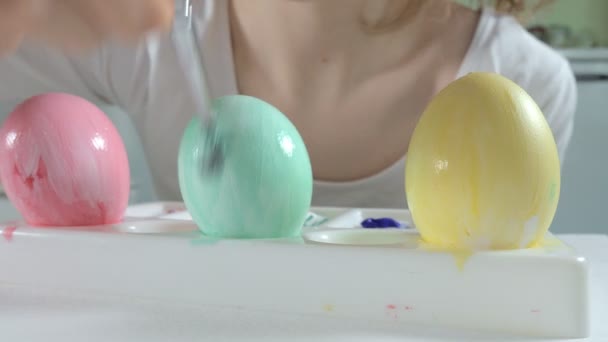 Una mujer pinta huevos de Pascua con pinturas de colores, primer plano — Vídeo de stock