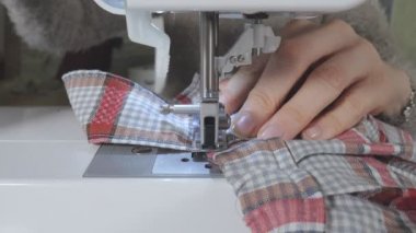Bir kadın dikiş makinesine dikiş dikiyor.