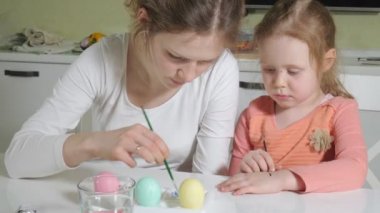 Anne ve kızı Paskalya yumurtaları renkli boya ile çizmek