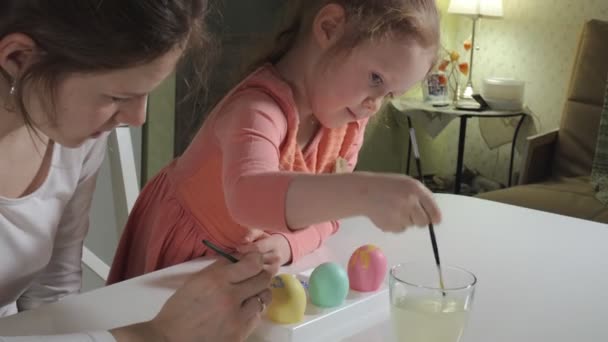 Мати і дочка малюють великодні яйця з кольоровими фарбами — стокове відео