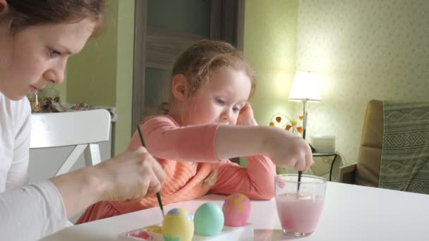 Мати і дочка малюють великодні яйця з кольоровими фарбами — стокове відео