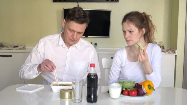 Una esposa y un marido están sentados en una mesa comiendo fideos chinos y verduras frescas. El concepto de nutrición adecuada y estilo de vida saludable — Vídeos de Stock