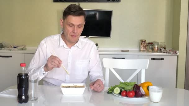 Una moglie e un marito sono seduti a un tavolo a mangiare spaghetti cinesi e verdure fresche. Il concetto di corretta alimentazione e stile di vita sano — Video Stock