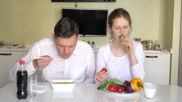 Uma esposa e marido está sentado a uma mesa comendo macarrão chinês e legumes frescos. O conceito de nutrição adequada e estilo de vida saudável — Vídeo de Stock