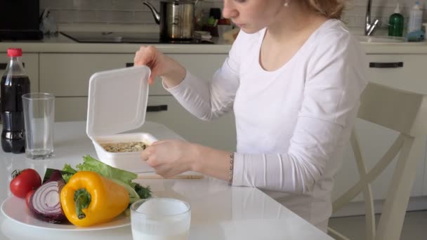 Una mujer está sentada en una mesa comiendo fideos chinos y verduras frescas. — Vídeo de stock