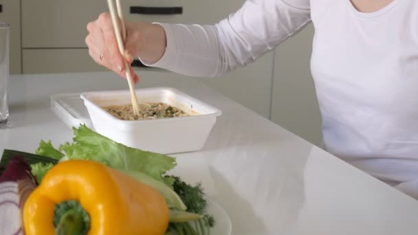Bir kadın Çin eriştesi ve taze sebze yeme bir masada oturuyor — Stok video