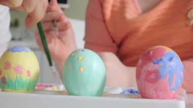 Anne ve kızı Paskalya yumurtaları renkli boya ile çizmek