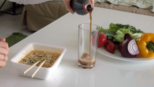 Una mujer está sentada en una mesa comiendo fideos chinos y verduras frescas. — Vídeos de Stock