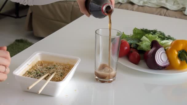 Een vrouw zit aan een tafel eten Chinese noedels en verse groenten — Stockvideo