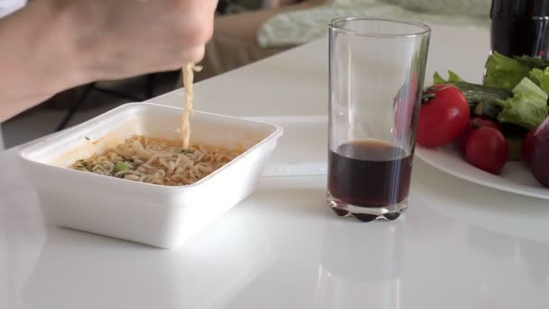 Eine Frau sitzt an einem Tisch und isst chinesische Nudeln und frisches Gemüse — Stockvideo