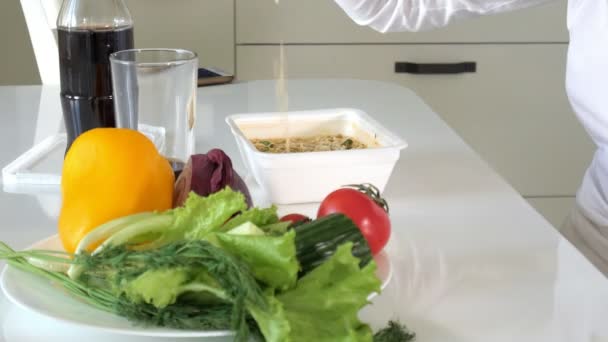 Una mujer está sentada en una mesa comiendo fideos chinos y verduras frescas. — Vídeo de stock