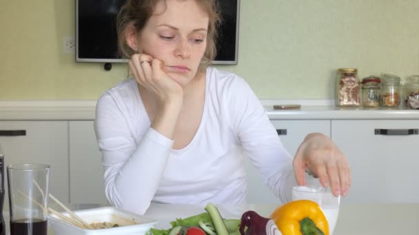 Una mujer está sentada en una mesa comiendo fideos chinos y verduras frescas. — Vídeo de stock