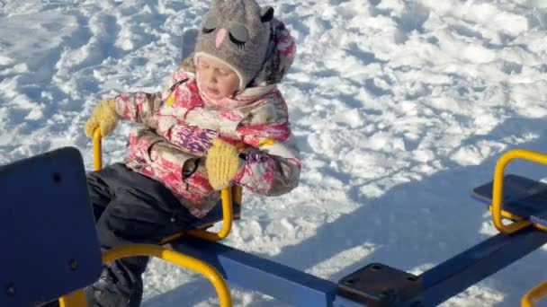 У зимовому парку дівчина на гойдалці — стокове відео