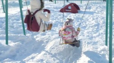 Genç anne çocuk salıncakta sallanan ile kış Park'ta açık ayarlayın. Kar düşüyor, kar, kış