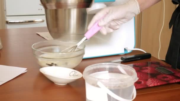 Женщина готовит тесто и крем для десерта макароны на домашней кухне, крупным планом — стоковое видео