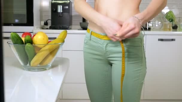 Mujer delgada medir la cintura en el fondo de un plato con frutas y verduras, un estilo de vida saludable — Vídeos de Stock
