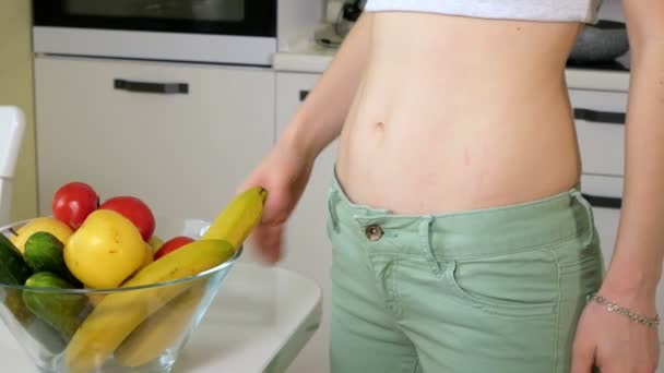 Femme mince mesurer la hanche sur le fond d'une assiette avec des fruits et légumes, un mode de vie sain — Video