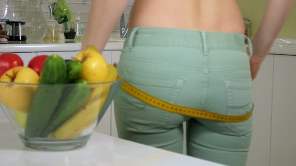 Mulher magra medir quadril no fundo de um prato com frutas e legumes, um estilo de vida saudável — Vídeo de Stock