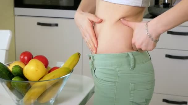 La donna magra misura la vita sullo sfondo di un piatto con frutta e verdura, uno stile di vita sano — Video Stock