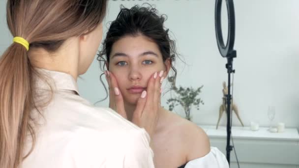 Jonge mooie vrouw aanbrengen van make-up door make-up kunstenaar — Stockvideo