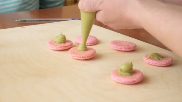 Chef hacer de un macaron entre los cuales es una crema. Cocinero hace hermosos postres con sus propias manos . — Vídeo de stock